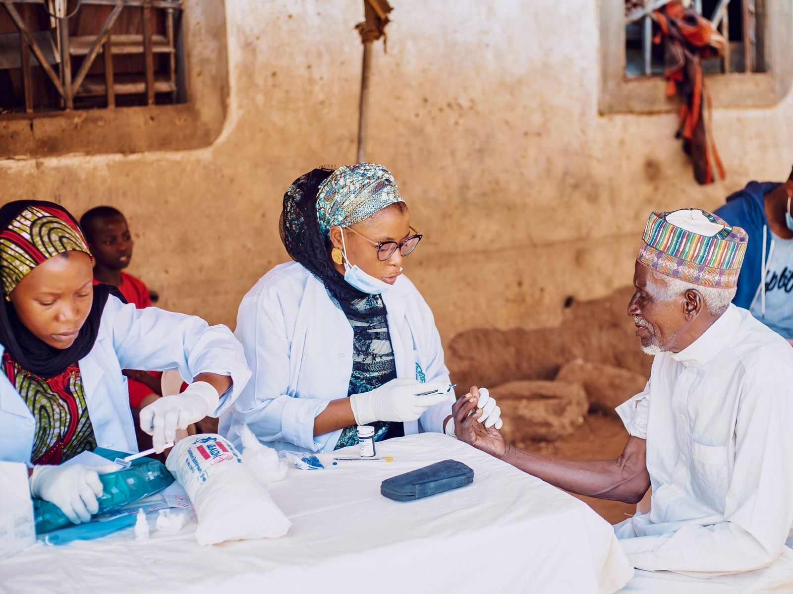 Health workers assisting an elderly man during community outreach in Kaduna